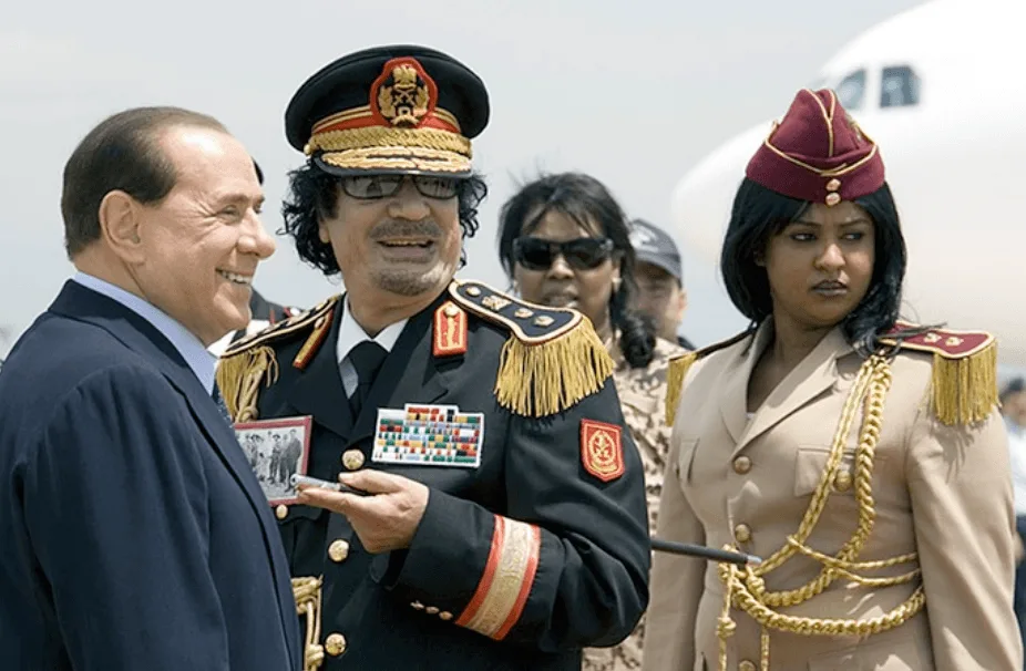 Muamar Gaddafi y Silvio Berlusconi en el aeropuerto de Roma, junio 2009