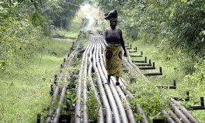 Un mujer camina sobre tuberías que transportan gas desde un yacimiento explotado por petroleras británicas.