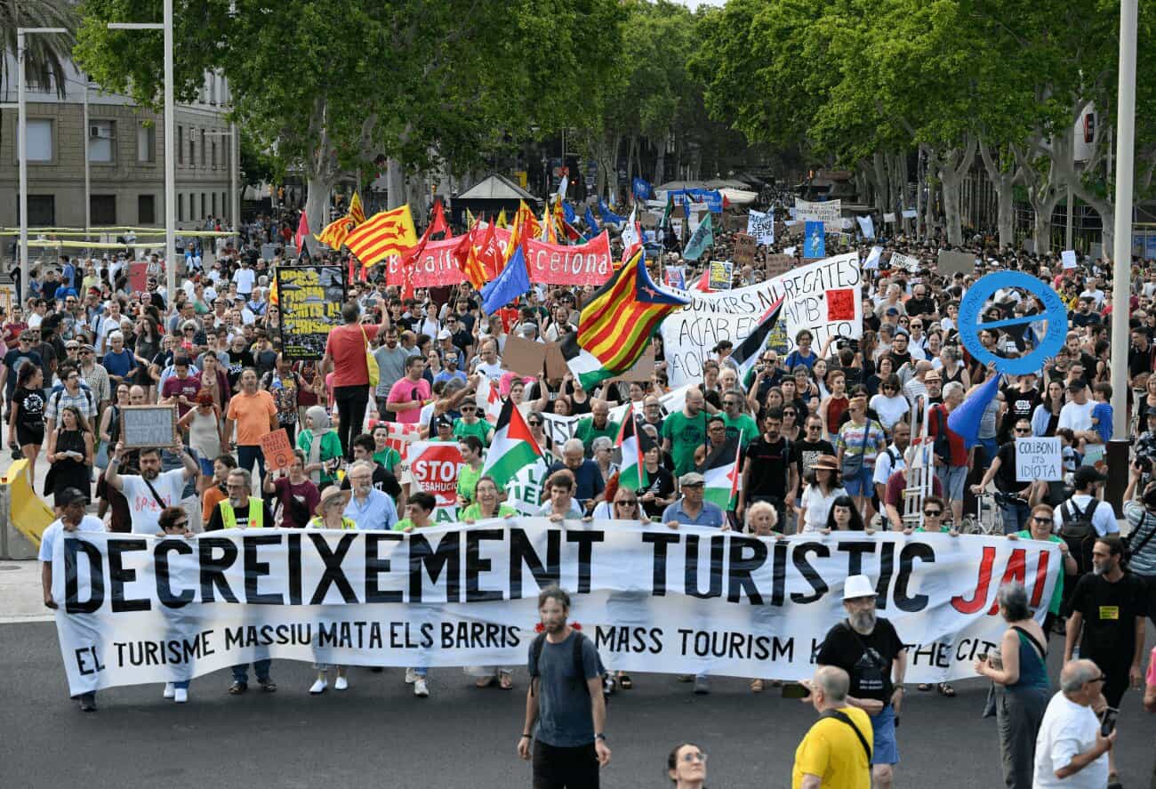 Manifestación contra el turismo masivo en Barcelona, con una gran pancarta que reza «Decreixement turístic ja! El turisme massiu mata els barris».